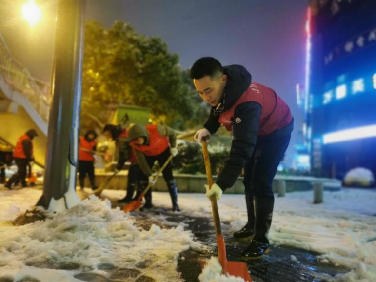 风雪午夜，志愿者正在加紧除冰扫雪。