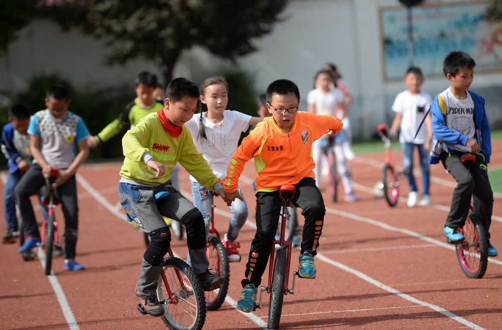 ↑2017年5月4日，西安市马腾空小学四年级学生王文博（前右）和魏小凯（前左）手拉手练习独轮车骑行。新华社记者李一博摄