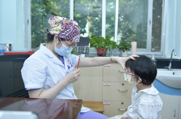 湖南省儿童医院眼科主任医师郭燕为萱萱做眼科检查。