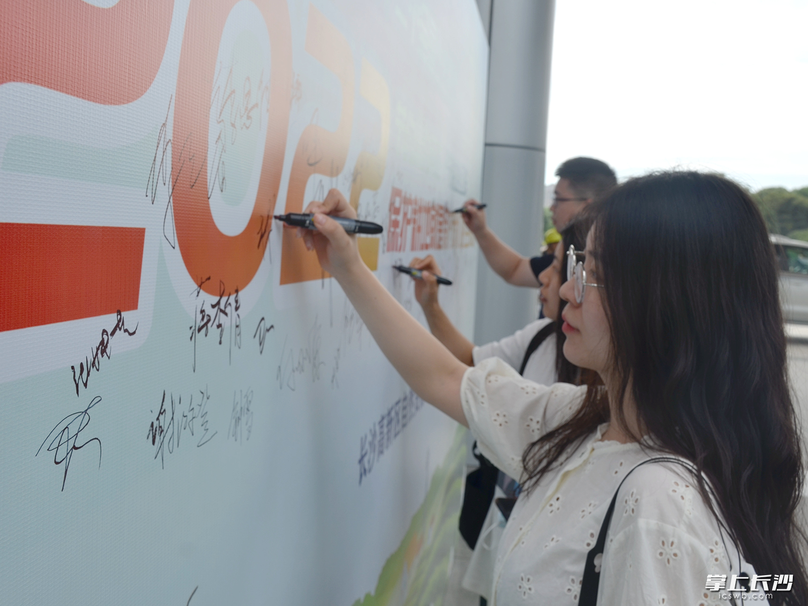 参与活动的群众纷纷在活动签名墙上写下自己的名字。