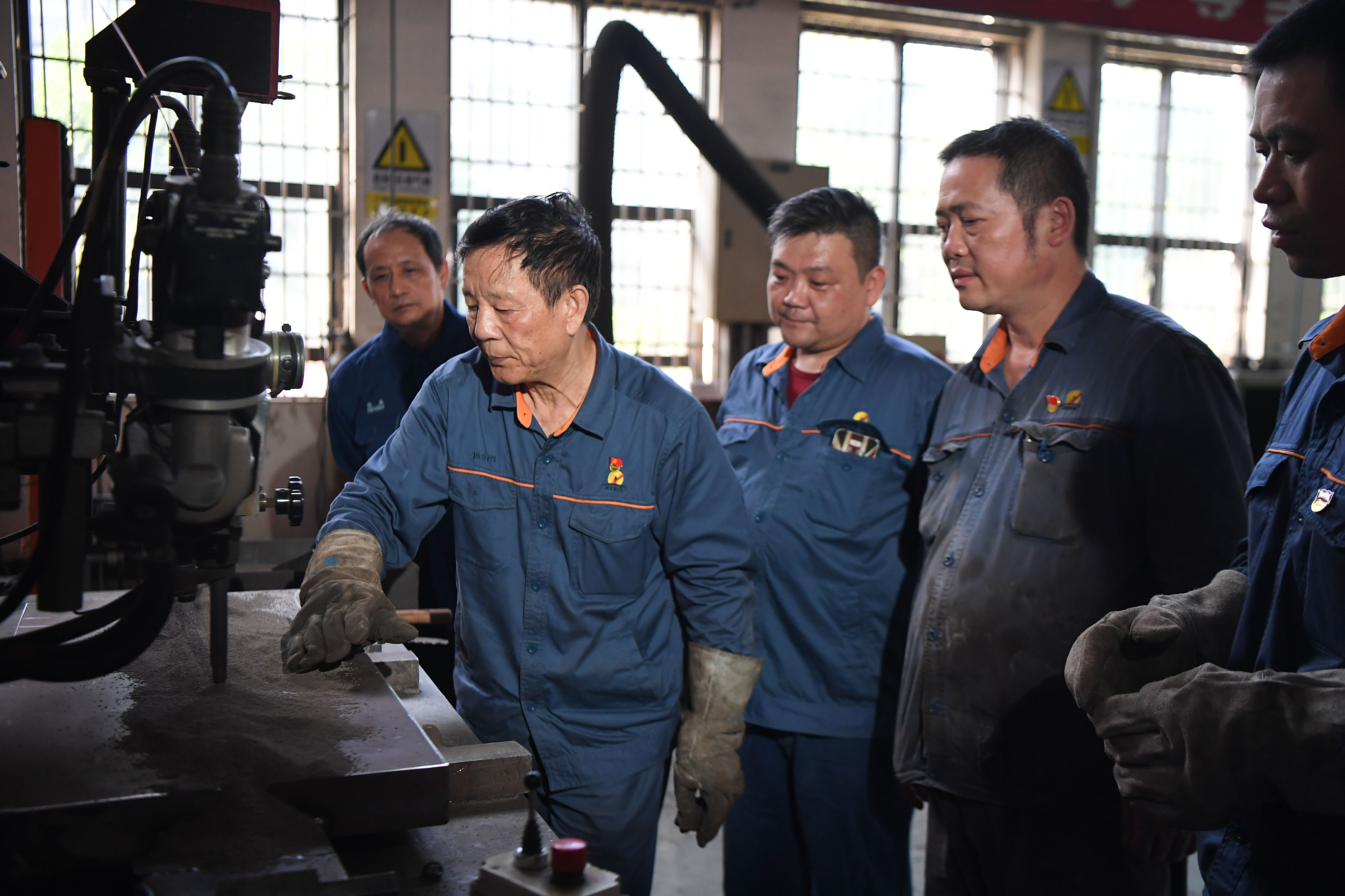 2021年6月12日，艾爱国（左二）在位于湖南湘潭的湖南华菱湘潭钢铁有限公司实验室内和同事探讨焊接技术。