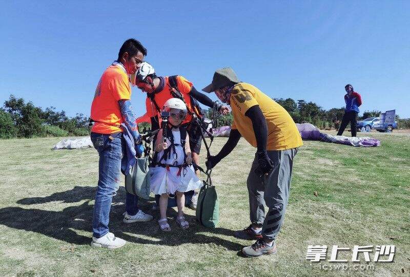 5岁的茜茜需要通过沙包“加重”飞行，图为教练们正细心检查装备。游客摄
