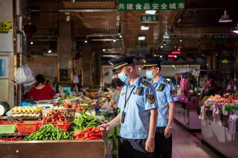 工作人员检查生鲜市场食品卫生状况。