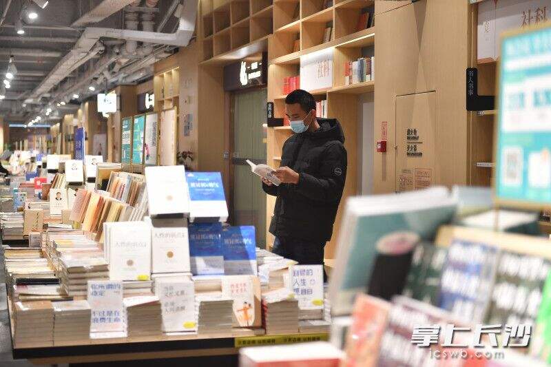位于大悦城的覔书店内，一位市民正在翻看书籍。