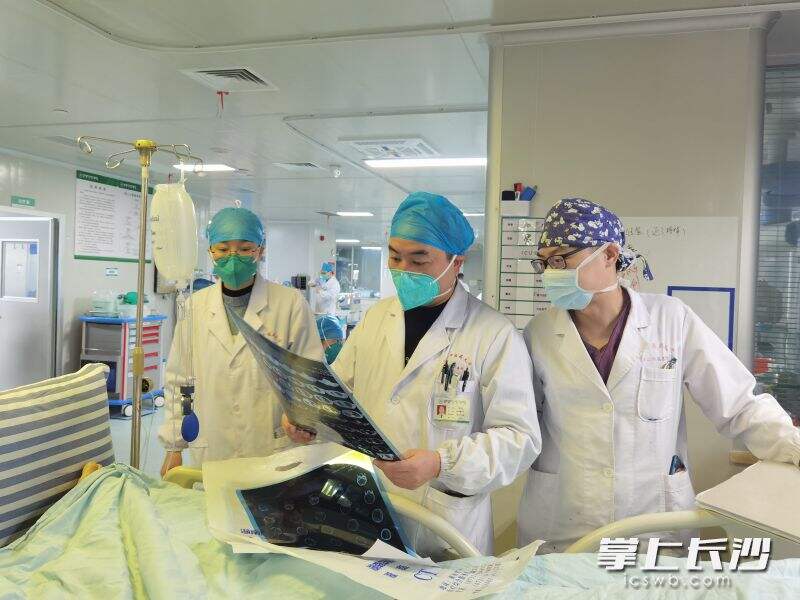 ICU二科负责人、副主任医师祁双林（中）带领医护人员在病人床旁查看其检查结果。