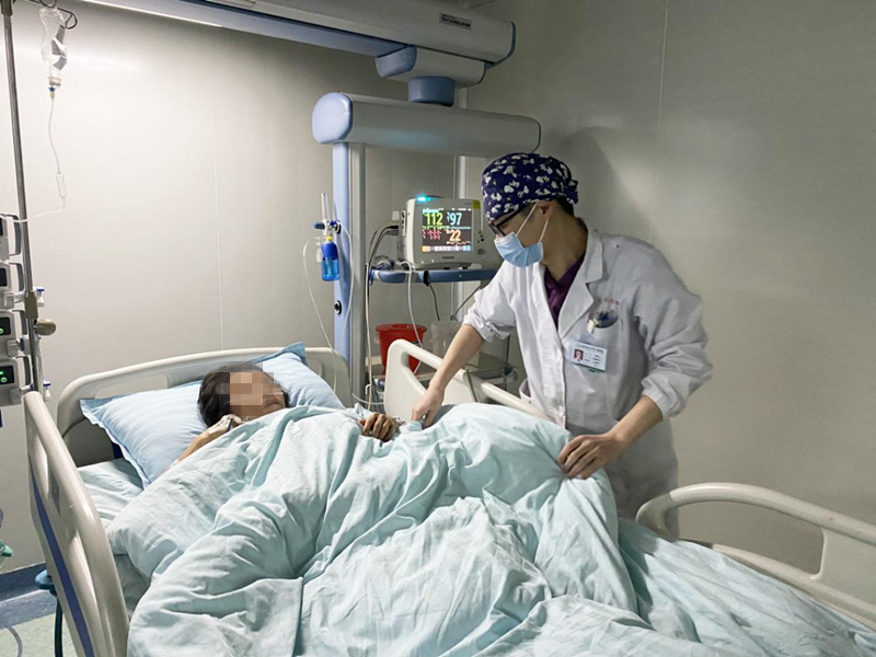 ICU吴奇伟医生在病房查看易女士病情，细心为她盖好被子。均由医院供图
