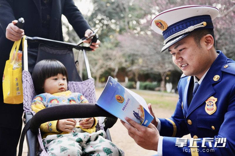 消防宣传员向过往群众发放并讲解消防安全知识手册。