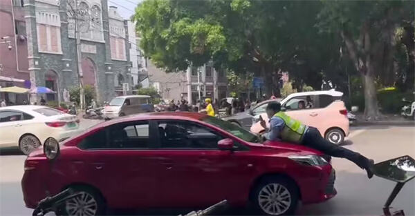 4月4日有网友在网上发出视频，有交通执法人员趴在一红色轿车的引擎盖上，车子向前行驶一段路程后被交通执法车辆和一出租车相继拦截。