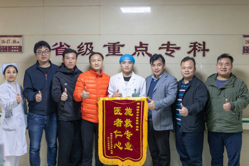 家属委托人将锦旗送到杨旺（左五）手中。学校供图