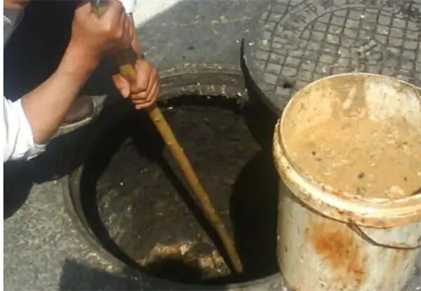 男女配合当街开井盖用勺挖取地沟油