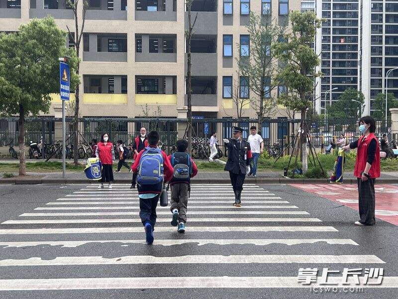 李少坤在校门口的斑马线前护送孩子过马路。长沙晚报全媒体记者 刘俊 摄