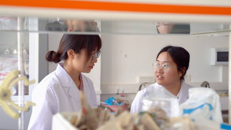 ▲　 王海丹（右）与同事在实验室探讨包材问题。孟云归▕摄