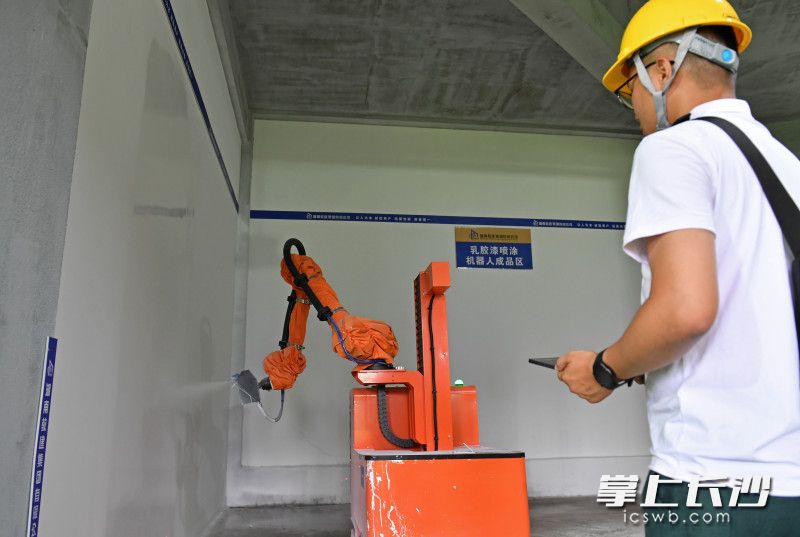 6月15日，望城区国欣·云境府项目工地上，工人操作室内喷涂机器人在紧张忙碌。