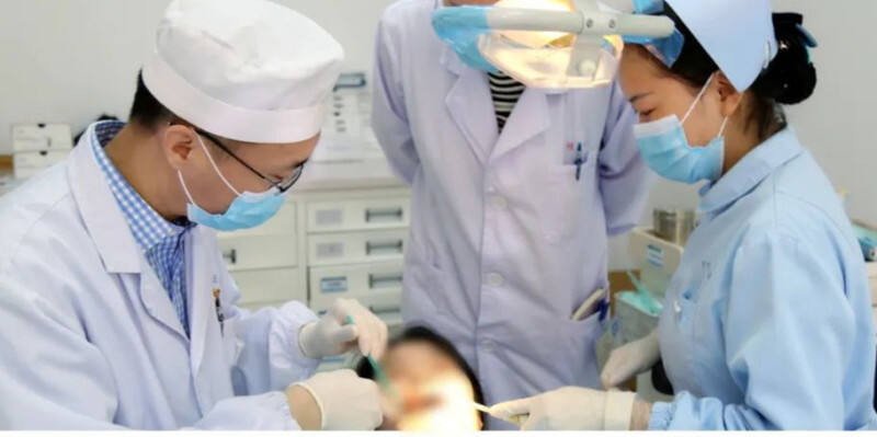 长沙市口腔医院正畸科主任、主任医师白明海（左）在为患者做正畸治疗。医院供图