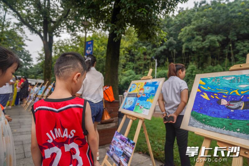 孩子们驻足观看“防溺水”主题画展。