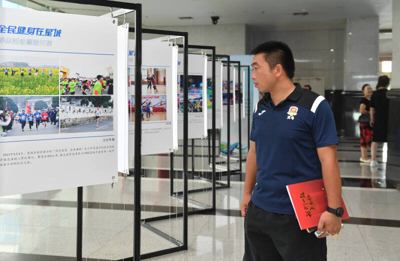 8月7日上午，“全民健身在星城”2023年长沙市体育摄影图文展在市政府大厅展出，市民们正在观看展览。