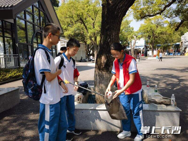 同学们在烈士公园捡拾垃圾，清洁环境卫生。