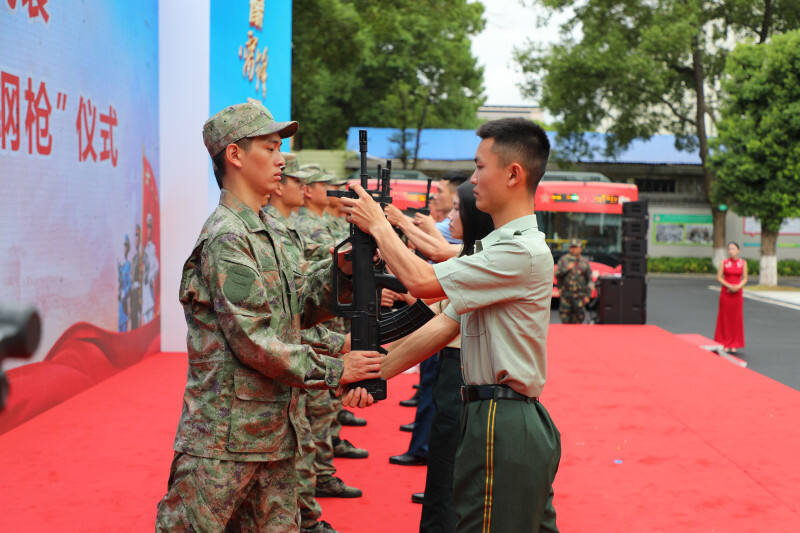 新兵代表从退役老兵手上接过钢枪。