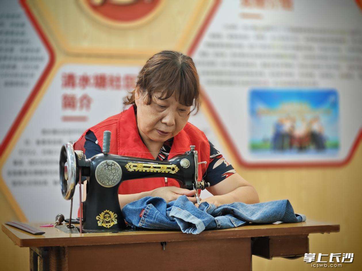 清水塘社区新时代文明实践站志愿者刘冬梅为居民缝补衣服。周子豪 摄