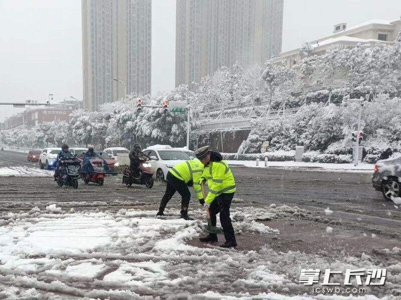 长沙县交警组织警力对路口人行道积雪进行清理，确保行人出行安全。