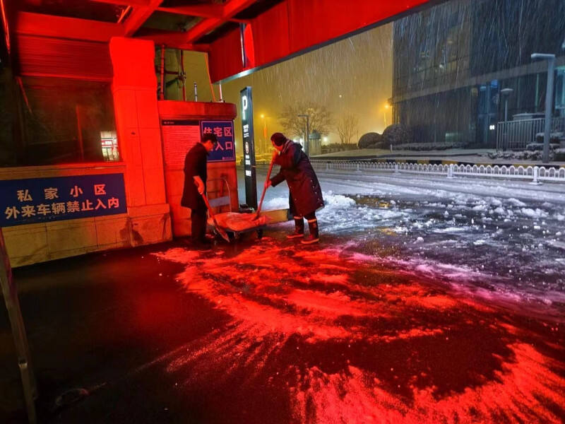 保利国际广场的物业人员连夜扫雪除冰。