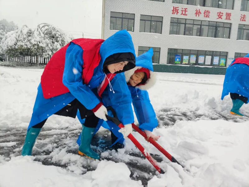 10岁的刘语惜与志愿者一起铲雪。