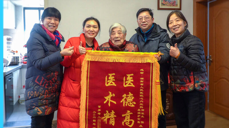 刘娭毑与家人为上门义诊的医护人员送上锦旗表达感谢。