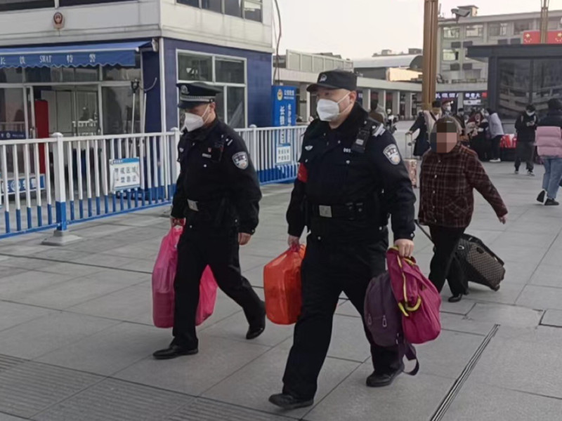 民警帮老人提行李赶车。