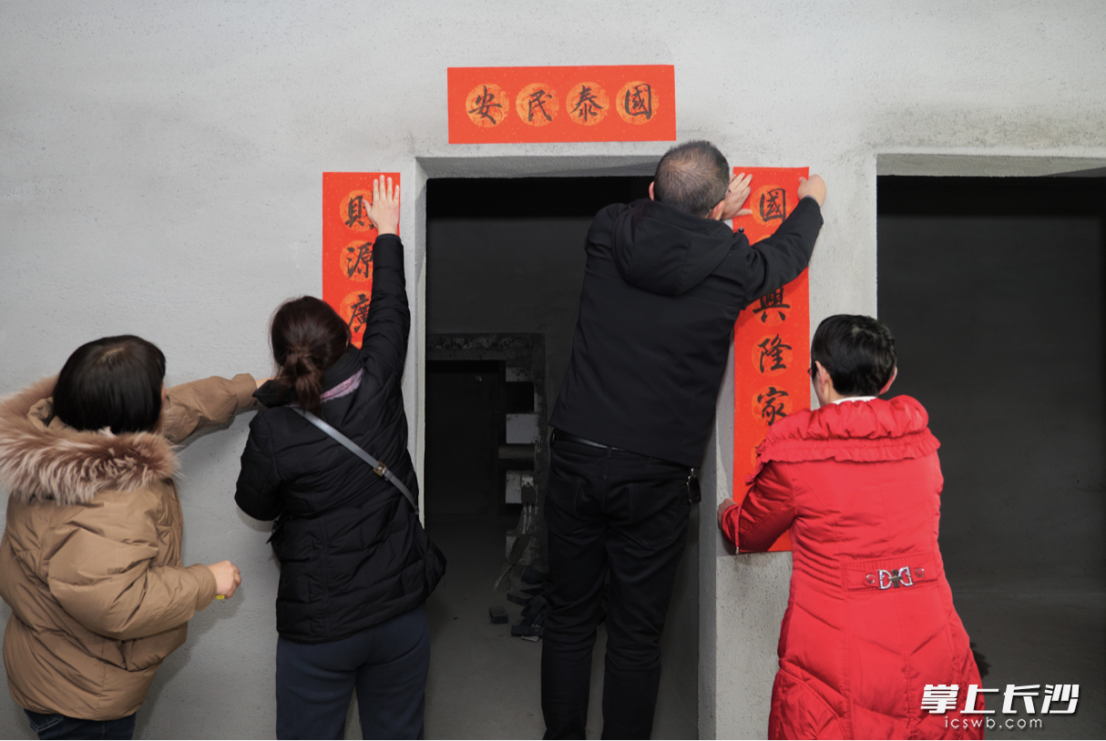 戴素萍和居民代表将火红的春联挂到新房的单元门口。