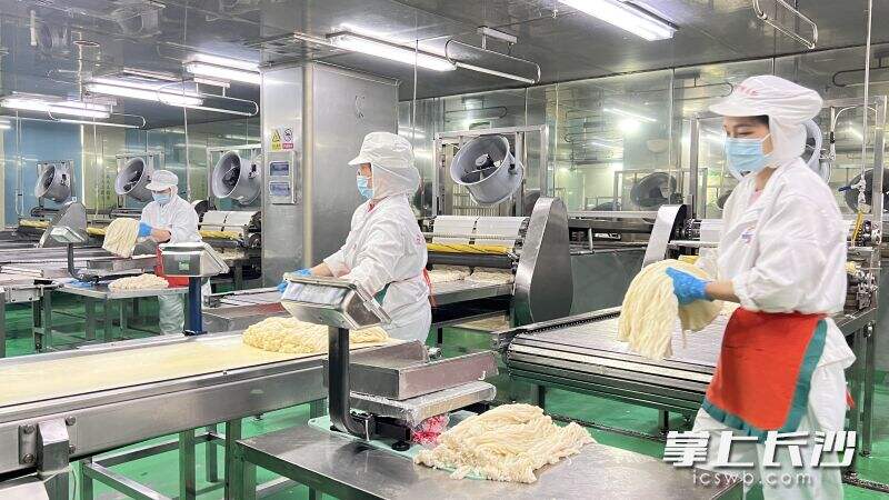 “银洲食品”生产车间里，工作人员在忙前将米粉称重封包。长沙晚报全媒体记者  周辉霞 摄