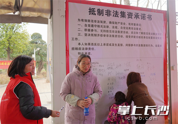 村民在“抵制非法集资承诺书”背景墙上签字。