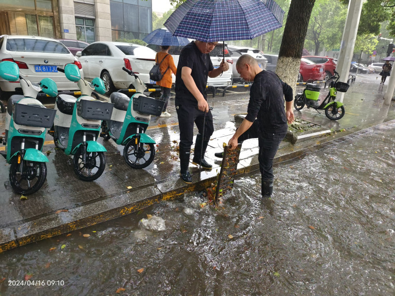 网格员方建兴撸起衣袖，冒雨徒手将堵塞在下水道的树枝杂物都清理出来。