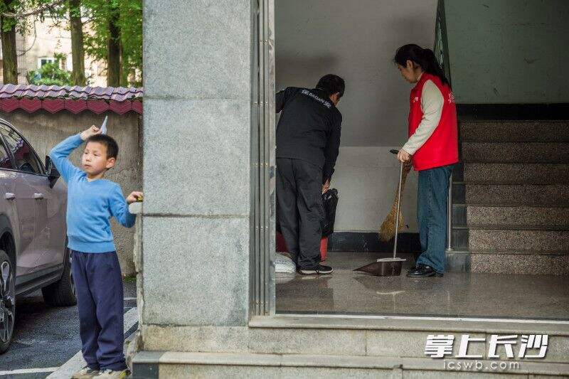 小区卫生检查也是片长的日常工作之一，看到楼道里有点乱，刘伟华跟物业工作人员一起收拾。