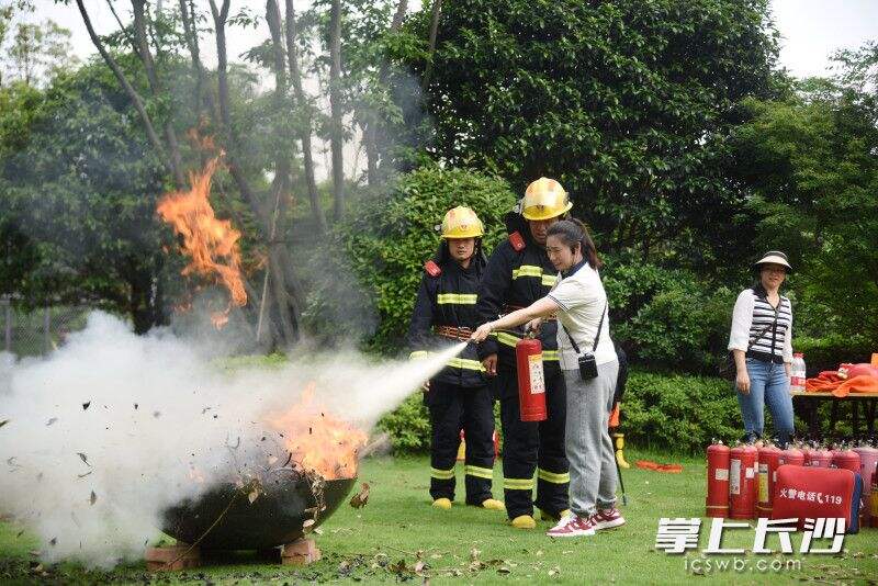 市民在消防员的指导下使用干粉灭火器灭火。