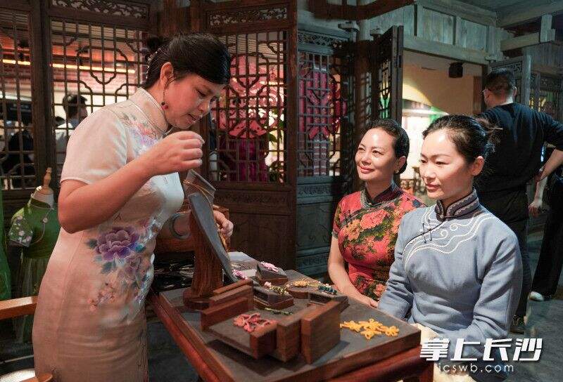 非遗技艺传承人正向游客讲解旗袍盘扣技艺。