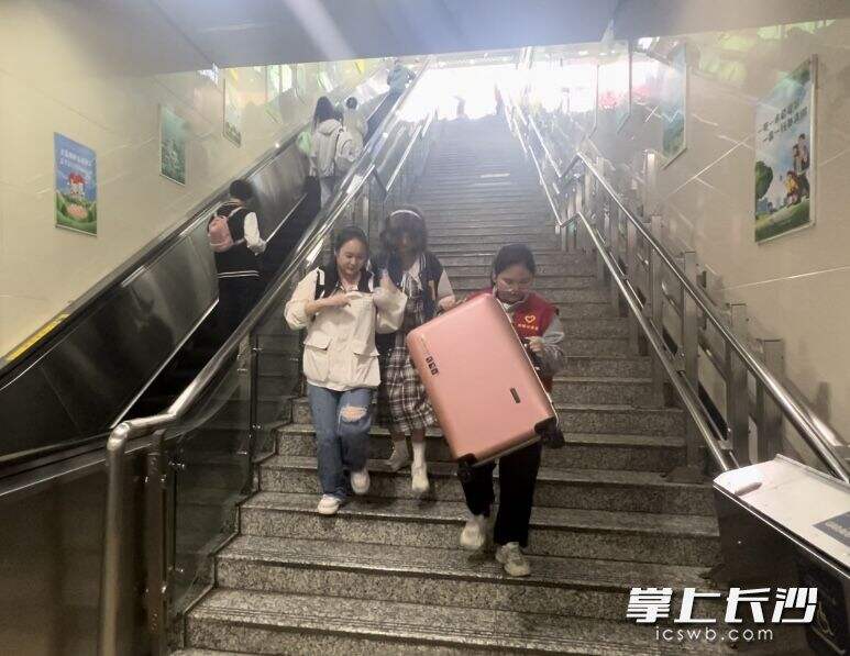 谢玉香（右）在地铁站帮助游客提行李。  均为长沙晚报全媒体记者刘俊摄