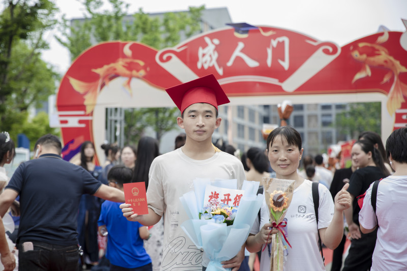 一名高三学生在“成人门”前和家人合影留念。