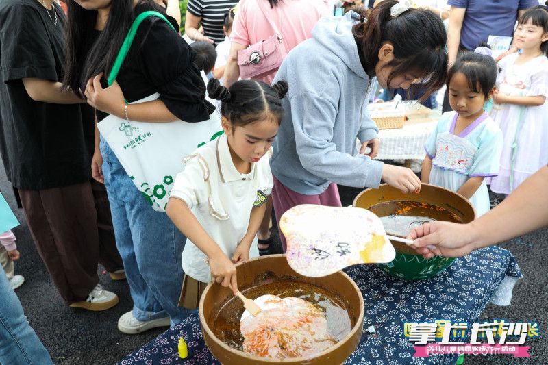 在非遗漂漆铺，萌娃将扇子放入水缸，不一会儿一把把漂亮的扇子就完成了。