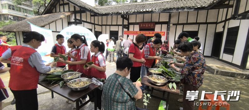 在新民学会旧址小院内，老人和小孩一同包粽子，人们希望端午传统美食能代代相传。